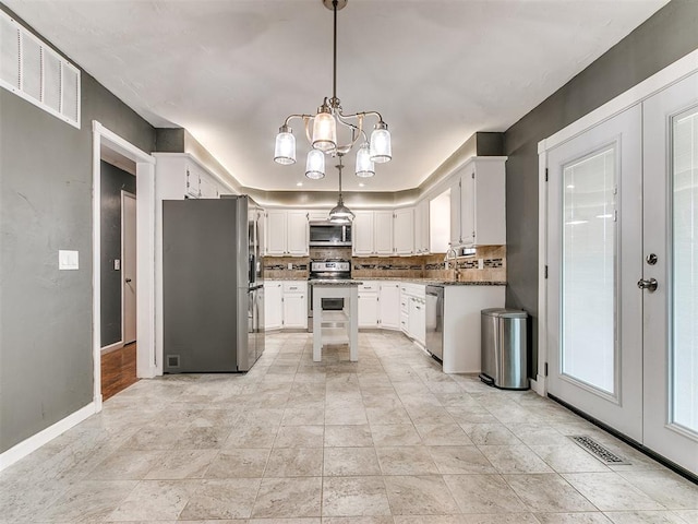 kitchen featuring an inviting chandelier, backsplash, stone countertops, white cabinets, and appliances with stainless steel finishes