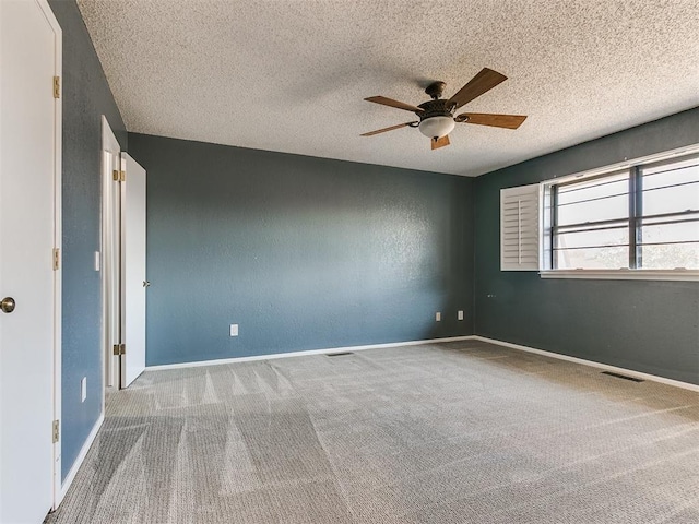 carpeted empty room with ceiling fan and a textured ceiling