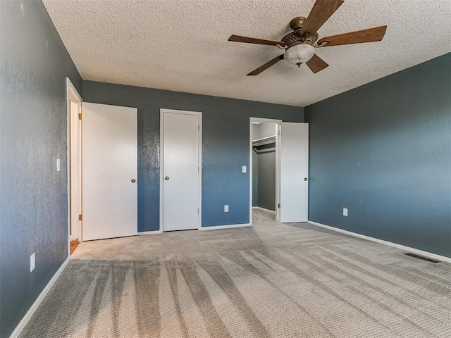 unfurnished bedroom featuring light carpet, a textured ceiling, and ceiling fan