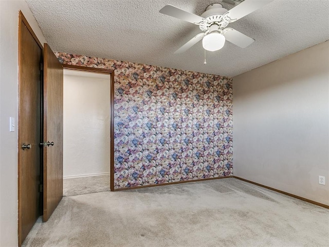 carpeted empty room with a textured ceiling and ceiling fan