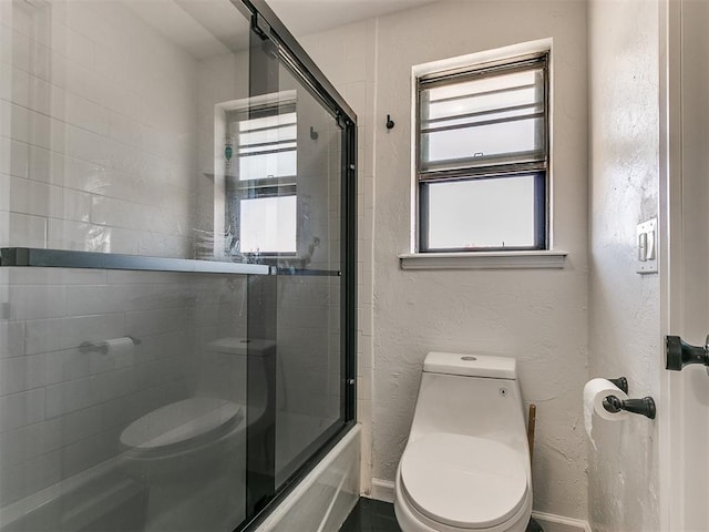 bathroom featuring combined bath / shower with glass door and toilet