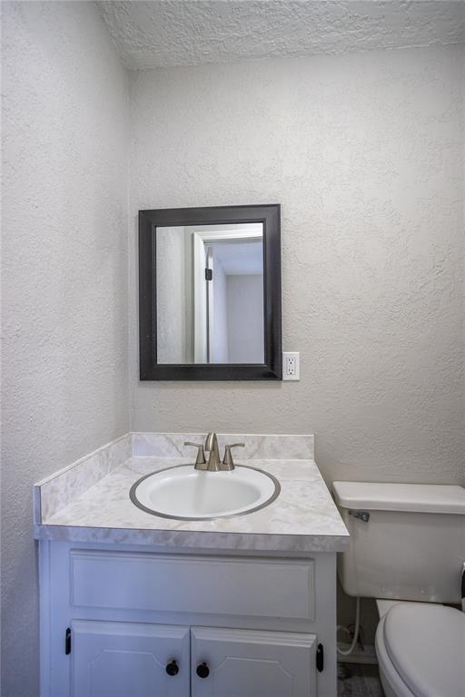 bathroom with vanity, a textured ceiling, and toilet