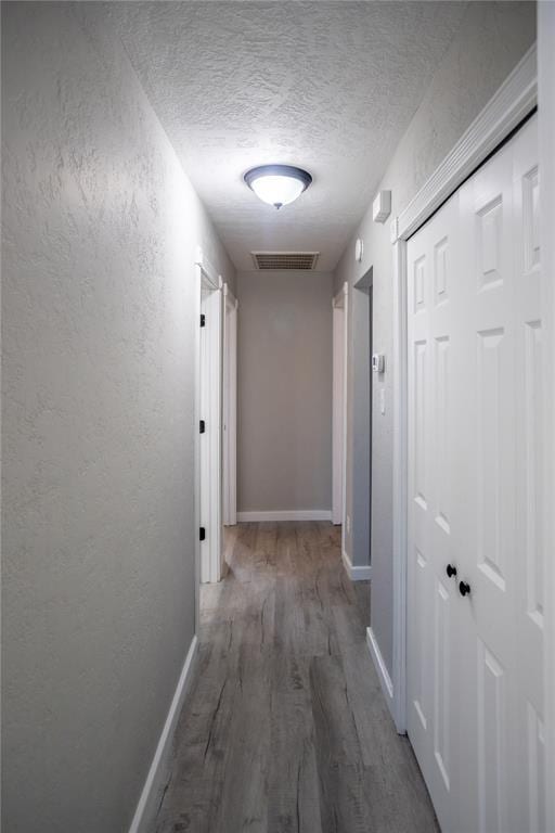 hall featuring a textured ceiling and dark hardwood / wood-style flooring