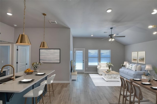 interior space with light hardwood / wood-style floors, decorative light fixtures, sink, and a breakfast bar area