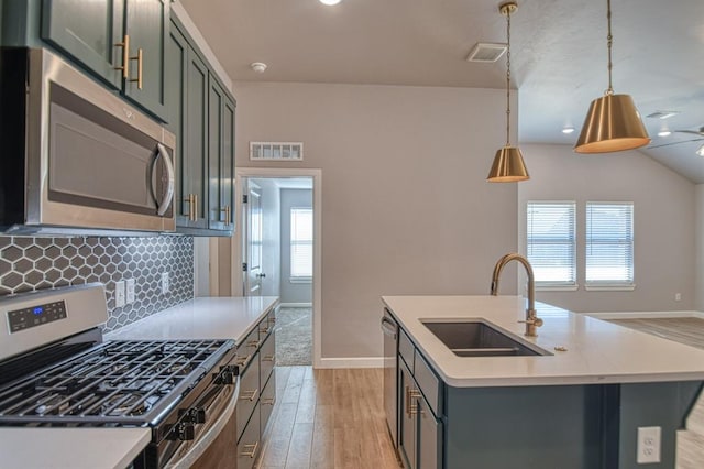 kitchen featuring appliances with stainless steel finishes, an island with sink, a wealth of natural light, sink, and decorative light fixtures