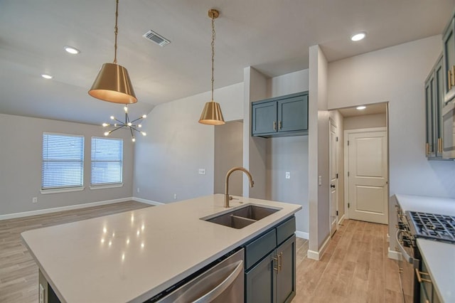 kitchen with sink, stainless steel appliances, hanging light fixtures, a center island with sink, and a chandelier