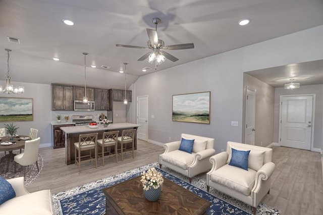 living room featuring ceiling fan, vaulted ceiling, and light wood-type flooring