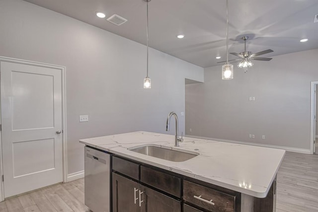 kitchen featuring an island with sink, dishwasher, sink, and dark brown cabinetry