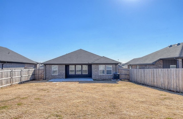 rear view of property featuring a yard, central AC unit, and a patio area