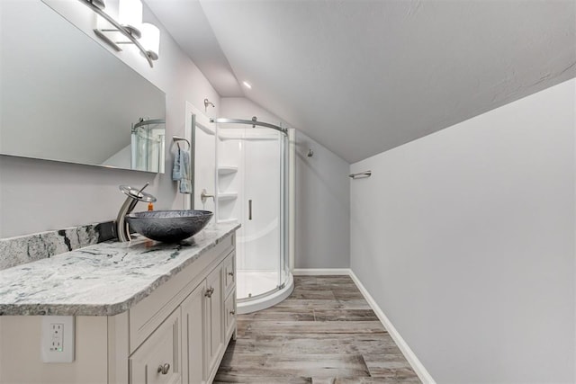 bathroom with vanity, wood-type flooring, vaulted ceiling, and walk in shower