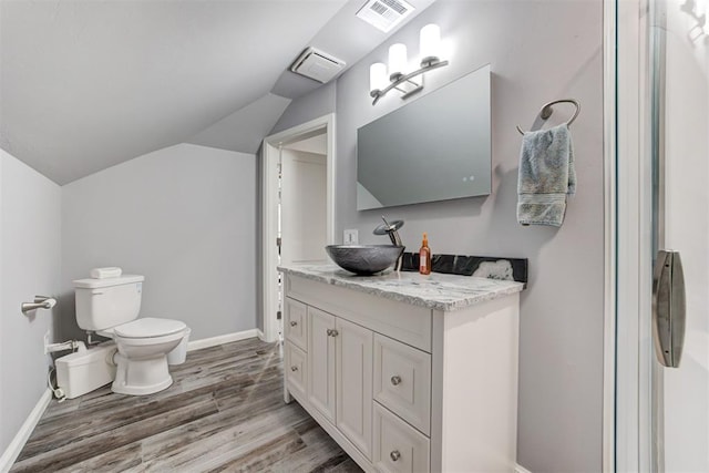 bathroom with hardwood / wood-style floors, vanity, vaulted ceiling, and toilet