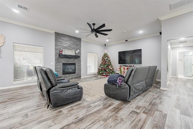 living room with ceiling fan, a fireplace, ornamental molding, and light hardwood / wood-style flooring