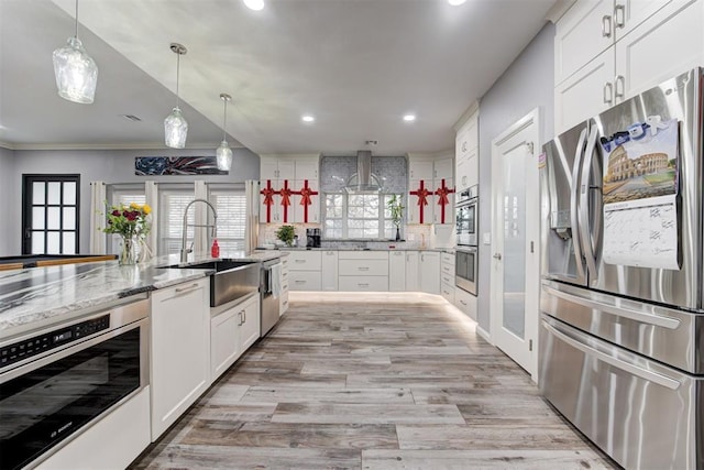 kitchen featuring light stone countertops, appliances with stainless steel finishes, backsplash, sink, and white cabinets