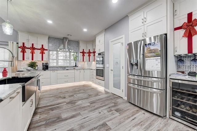 kitchen featuring white cabinetry, wall chimney exhaust hood, beverage cooler, backsplash, and appliances with stainless steel finishes