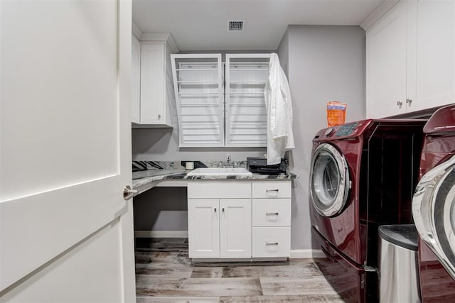 clothes washing area featuring cabinets, independent washer and dryer, light hardwood / wood-style flooring, and sink