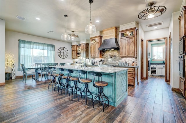 kitchen with hanging light fixtures, a wealth of natural light, and dark wood-type flooring