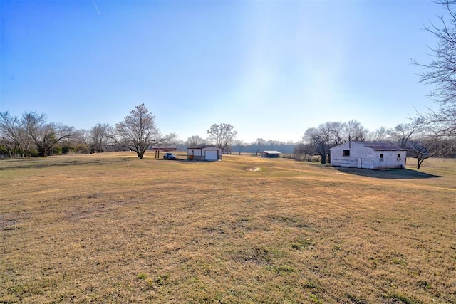 view of yard with a rural view, a garage, and an outdoor structure