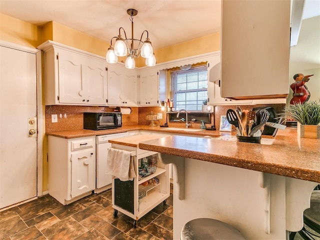 kitchen with hanging light fixtures, dishwasher, sink, and white cabinetry