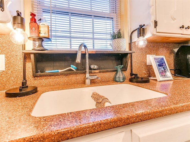 room details with white cabinets, tasteful backsplash, and sink