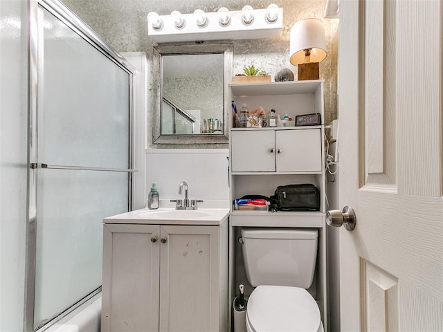 full bathroom featuring combined bath / shower with glass door, vanity, and toilet