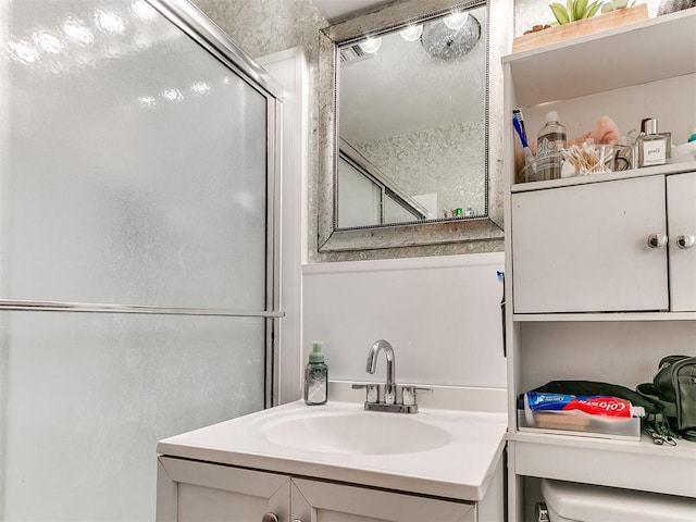 bathroom featuring a shower with shower door, toilet, and vanity