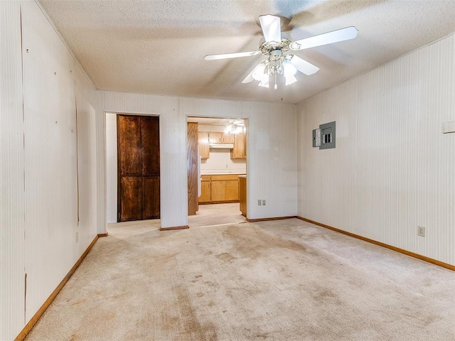 carpeted spare room with electric panel, ceiling fan, and a textured ceiling