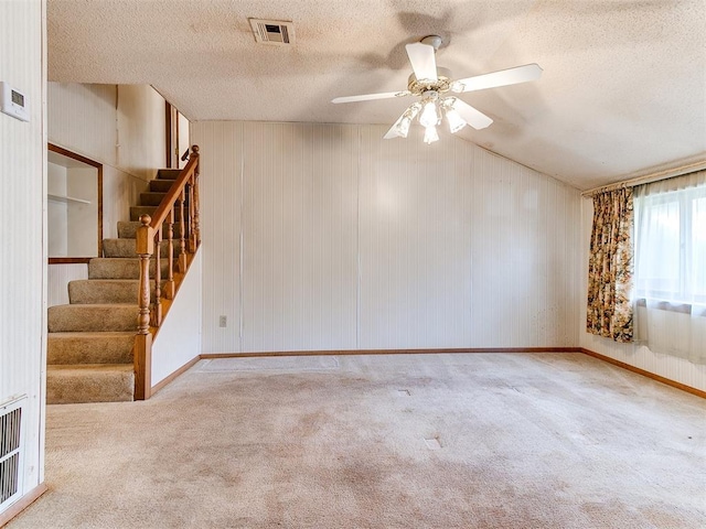 spare room featuring a textured ceiling, ceiling fan, light colored carpet, and lofted ceiling