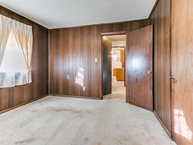 empty room with wood walls and light colored carpet