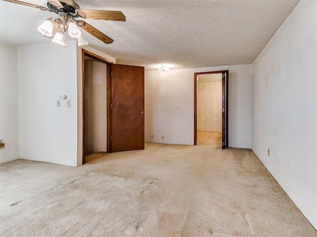 unfurnished room with ceiling fan, light colored carpet, and a textured ceiling