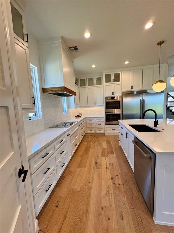8409 NW 128th St, Oklahoma City, OK 73142 - kitchen with appliances with stainless steel finishes, a sink, light wood finished floors, white cabinets, and recessed lighting
