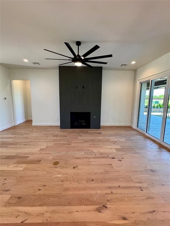8409 NW 128th St, Oklahoma City, OK 73142 - unfurnished living room with light wood finished floors, baseboards, ceiling fan, recessed lighting, and a fireplace