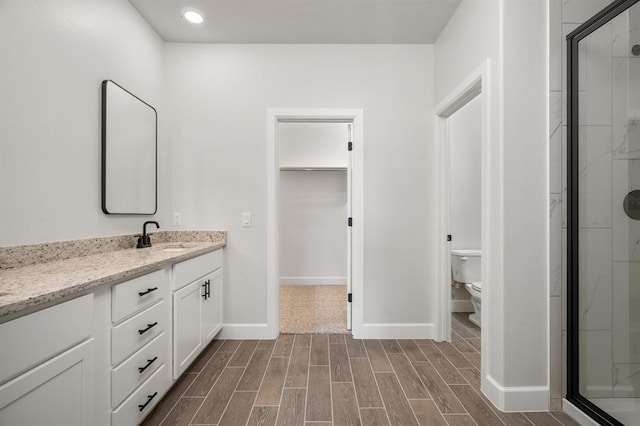 bathroom with a shower with door, vanity, and toilet