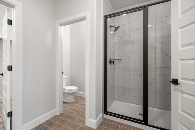 bathroom featuring a shower with shower door and toilet