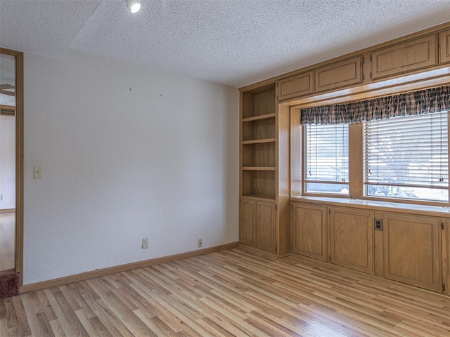 empty room featuring a textured ceiling and light hardwood / wood-style floors