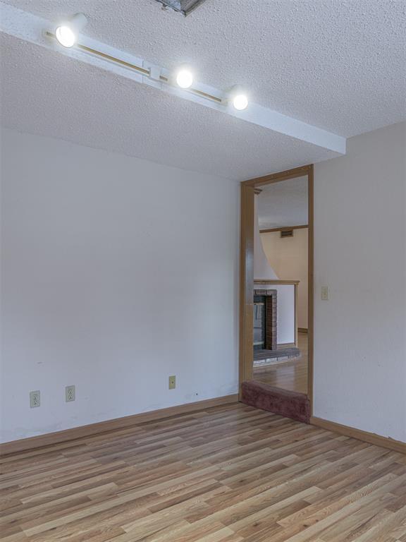 unfurnished room with a fireplace, light hardwood / wood-style floors, and a textured ceiling