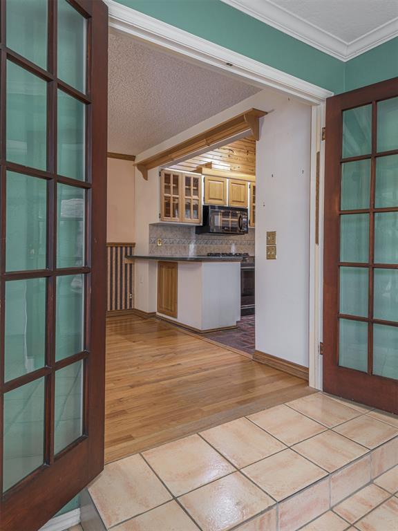 kitchen with light hardwood / wood-style flooring, crown molding, a textured ceiling, decorative backsplash, and black appliances