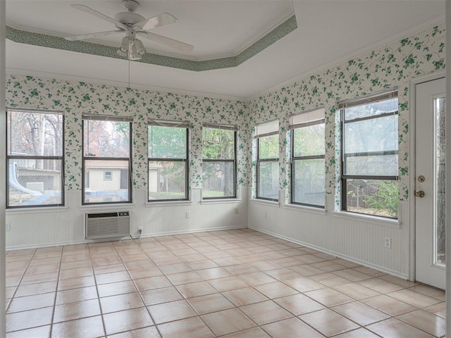 unfurnished sunroom featuring ceiling fan, a wall unit AC, and a tray ceiling