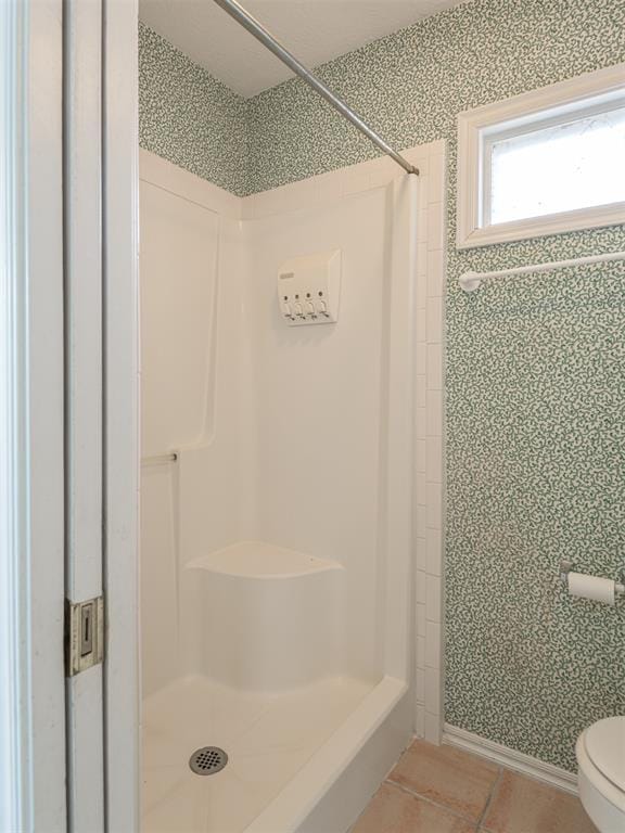 bathroom with a shower, tile patterned flooring, and toilet