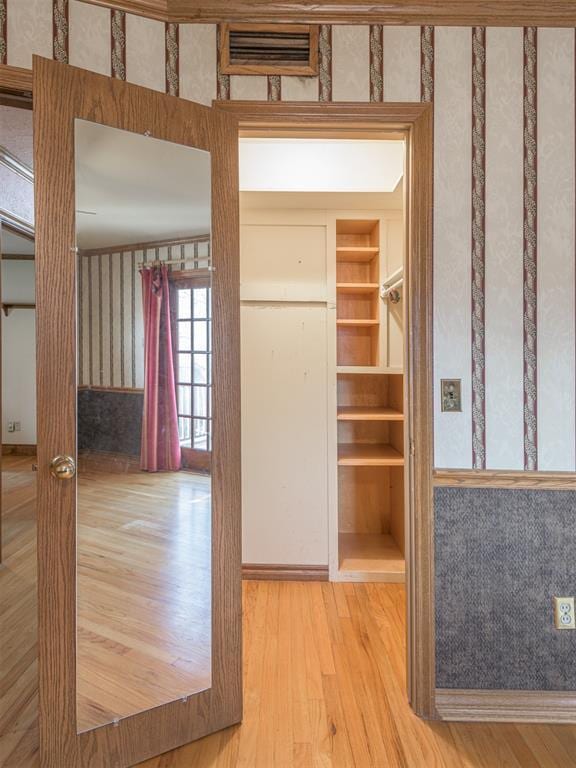 hall featuring built in shelves and wood-type flooring