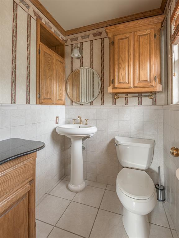 bathroom with tile patterned flooring, tile walls, and toilet