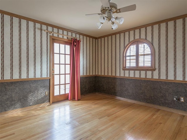 empty room with ceiling fan, light wood-type flooring, ornamental molding, and a wealth of natural light