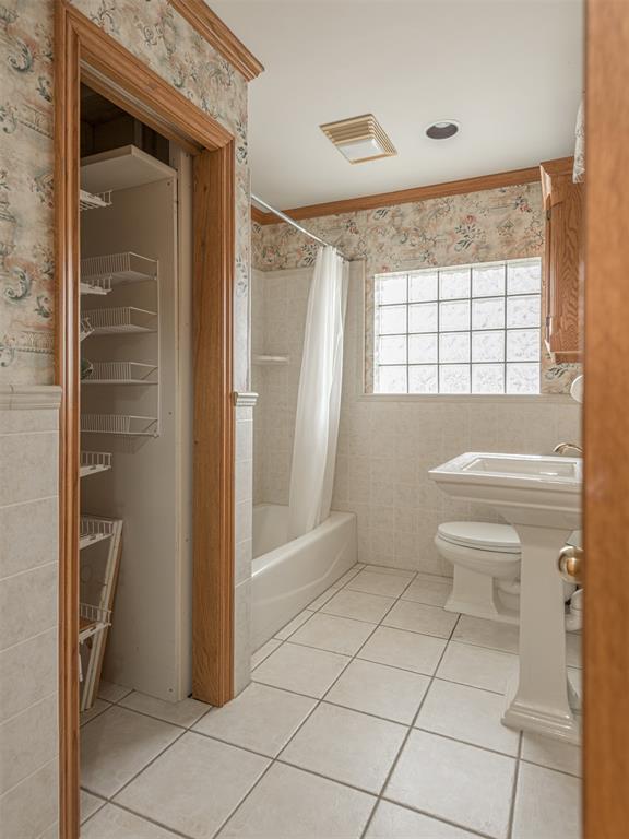 bathroom with tile patterned floors, ornamental molding, shower / tub combo, and toilet