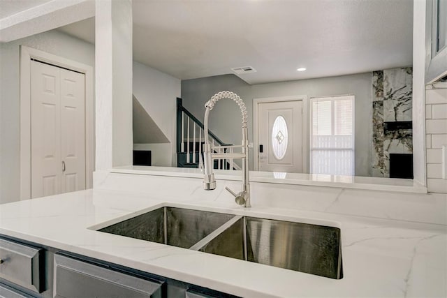 kitchen with sink, light stone countertops, and a fireplace