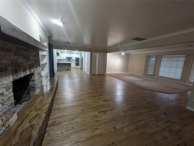 unfurnished living room with hardwood / wood-style flooring, a stone fireplace, and ornamental molding