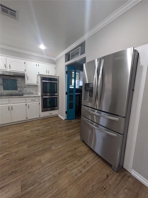 kitchen with dark wood-type flooring, white cabinets, crown molding, tasteful backsplash, and stainless steel appliances