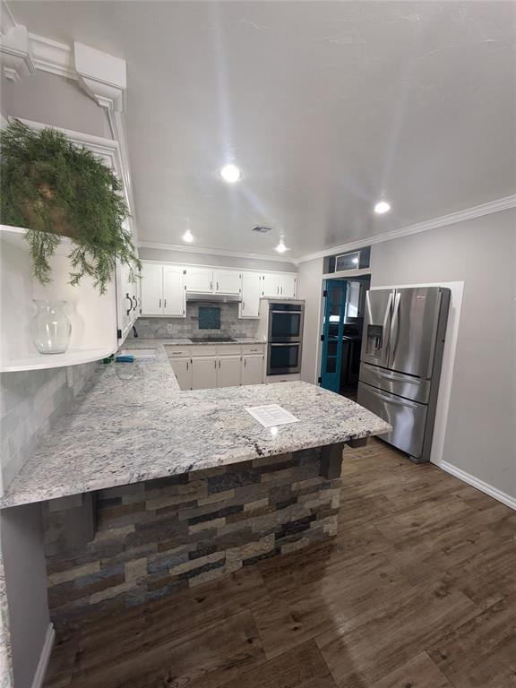 kitchen featuring dark hardwood / wood-style flooring, kitchen peninsula, stainless steel appliances, and tasteful backsplash