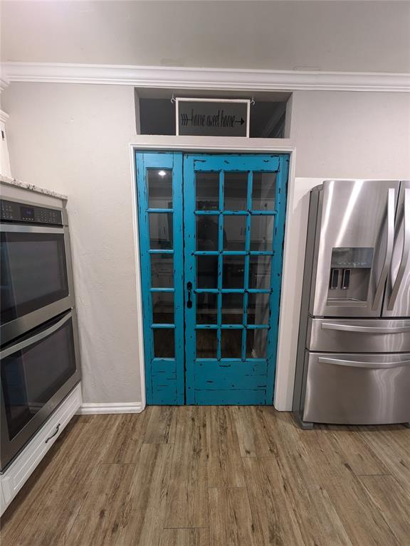 kitchen featuring wood-type flooring, ornamental molding, and appliances with stainless steel finishes