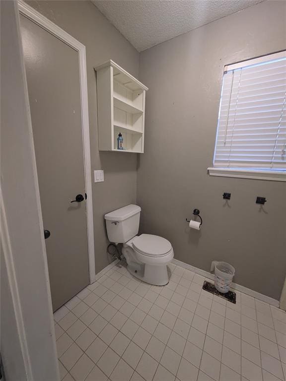 bathroom featuring tile patterned flooring, toilet, and a textured ceiling