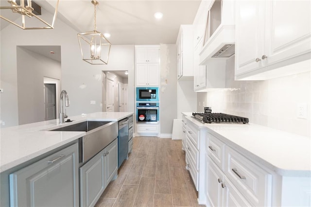 kitchen with white cabinets, a sink, light wood-style flooring, stainless steel appliances, and decorative backsplash
