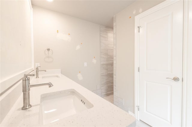 bathroom with a tile shower and a sink